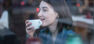 A young woman with a brown bob sips coffee from a white porcelain mug