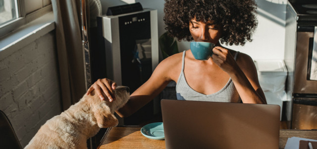 woman drinking coffee and patting a dog