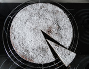 Round cake with one slice slightly removed. The cake is dusted with icing sugar.
